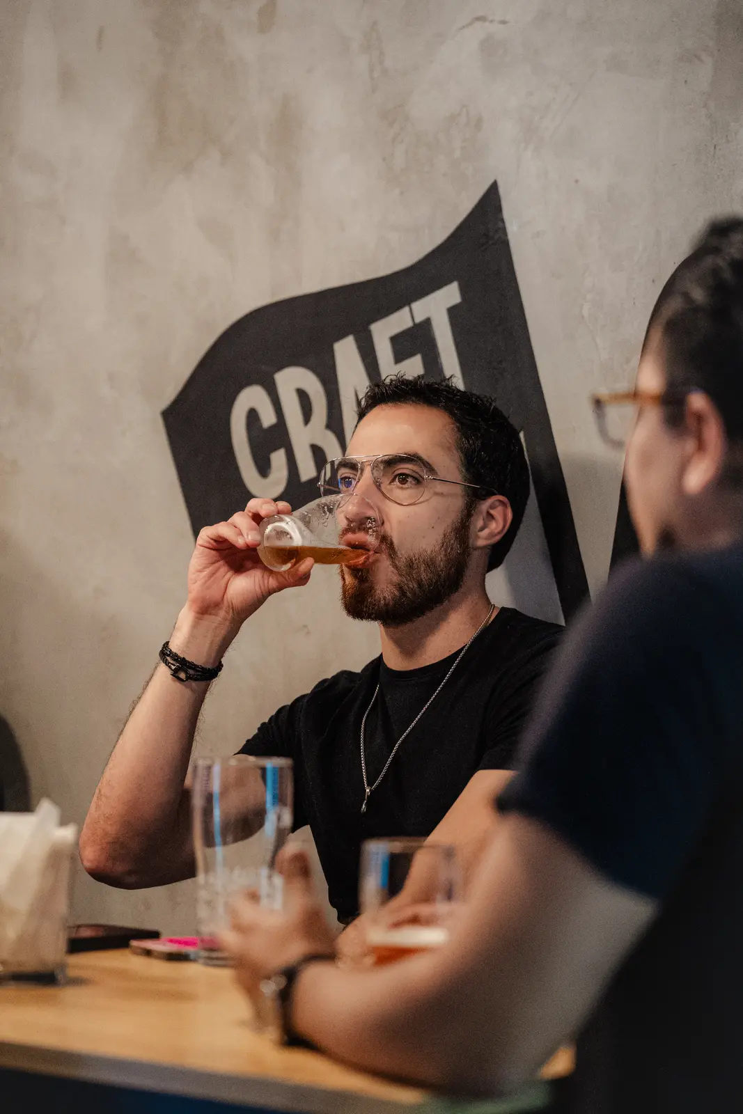 Cliente disfrutando una cerveza frente al mural de Craft Providencia